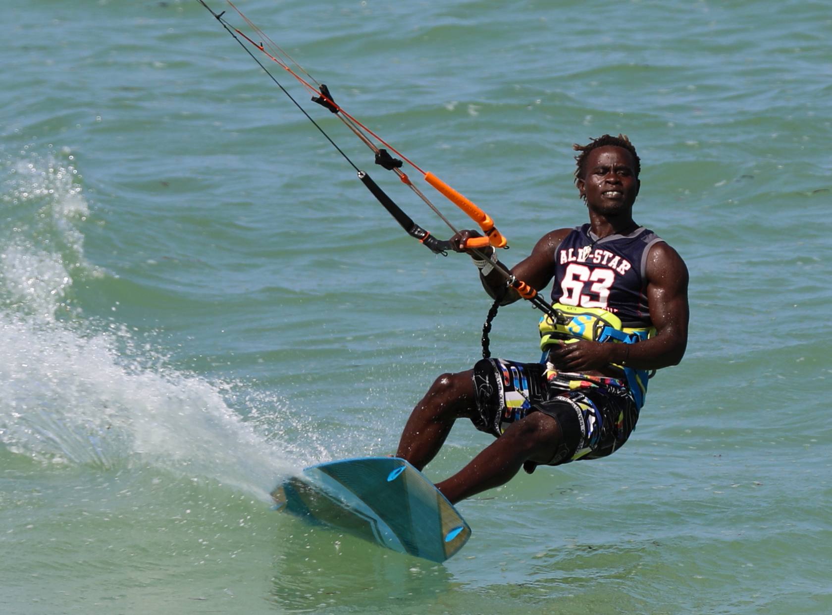 A kitesurfer carving across the turquoise Jambiani lagoon